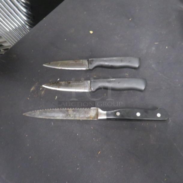 Assorted chef knives, 3-piece set, black handles, serrated and straight blades, used condition, no visible brand markings.