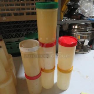 Stacked Store N Pour containers with various flat lids in red, green, and white. Used condition, ideal for organizing liquids.