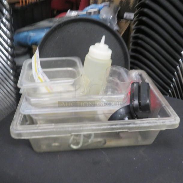 A collection of miscellaneous kitchen items including plastic trays, a squeeze bottle, and various utensils in a transparent bin.