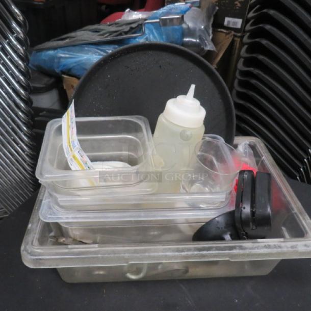 A mixed lot of miscellaneous kitchen items including containers, a plastic squeeze bottle, and a round black tray. Condition used.