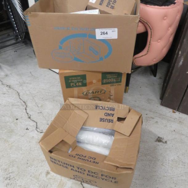 Two open cardboard boxes containing miscellaneous items, including wrapped rolls, on a concrete floor. Box labels visible.