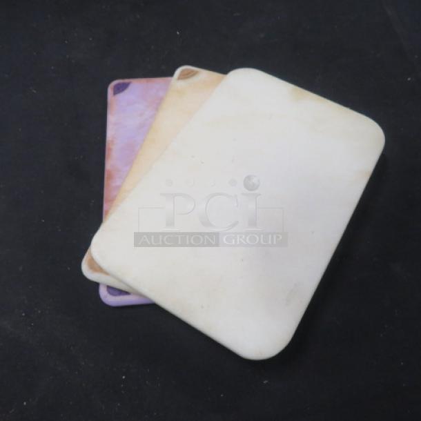 Assorted cutting boards, set of three, varying colors, gently used, visible surface wear, ideal for kitchen prep tasks.