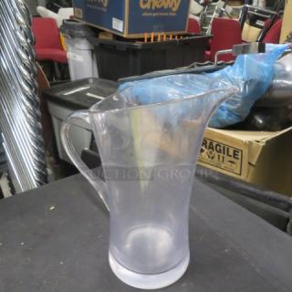 Clear plastic pitcher with handle, tapered spout, and frosted base. Slightly worn condition, suitable for liquids.