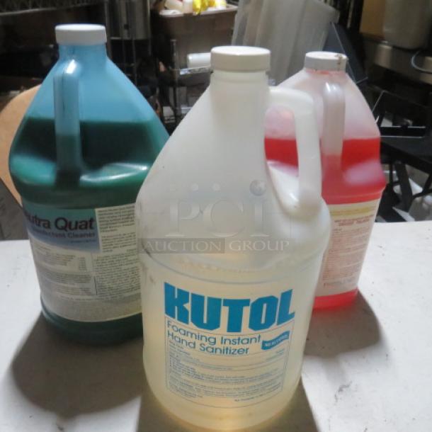 Three gallon-sized containers of assorted cleaner, including Kutol Foaming Instant Hand Sanitizer, with visible product labels.