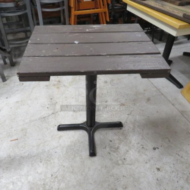 Wooden patio table with a pedestal base, measures 28x22x30 inches. Brown slatted top, metal base, used condition.