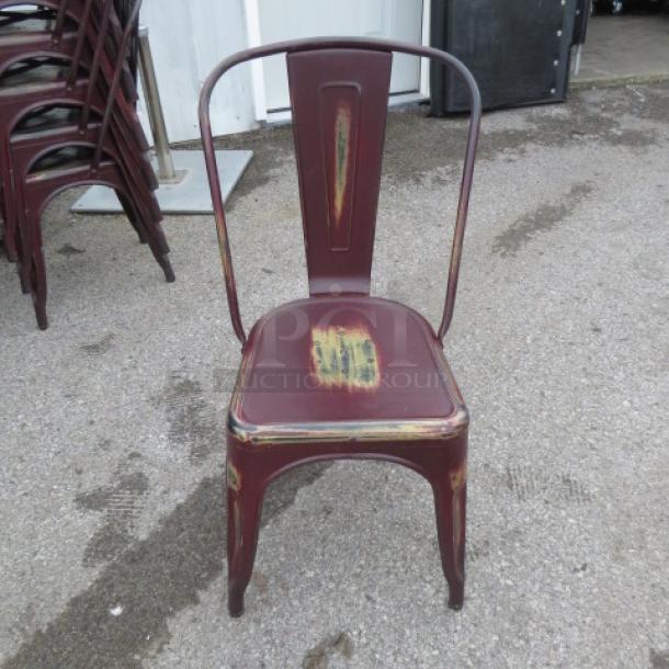 Industrial-look metal chair, distressed finish, suitable for indoor/outdoor use. Maroon color with rustic wear marks. Good condition.