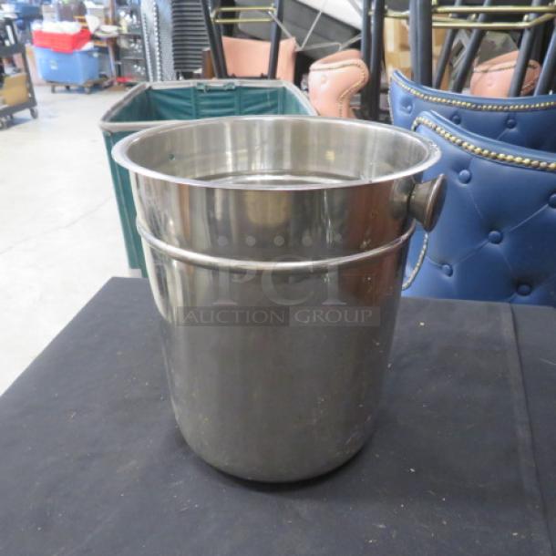 Stainless steel wine/champagne bucket, cylindrical with handle, reflective finish, excellent condition, suitable for elegant dining.