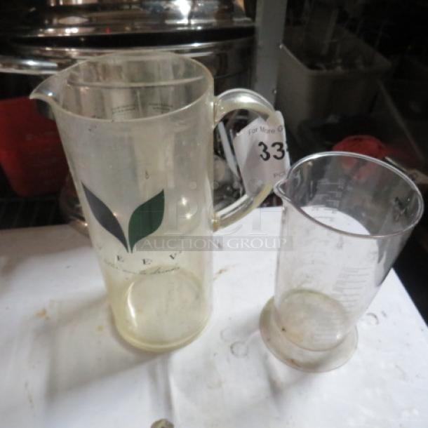 Clear glass pitcher set with leaf logo; includes large jug and smaller measuring jug with markings. Used condition.