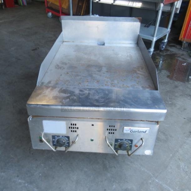 Garland natural gas griddle, stainless steel, 24x39x24 inches, visible signs of wear, dual control dials, brand label.