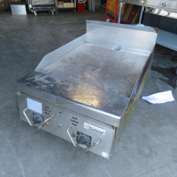 Garland natural gas griddle, 24x39x24 inches, stainless steel, dual controls, visible wear, brand logo on front panel.