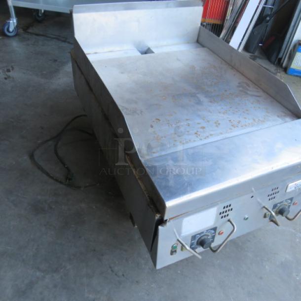 Garland natural gas griddle, 24x39x24 inches, stainless steel, used condition with visible surface wear, featuring control knobs.