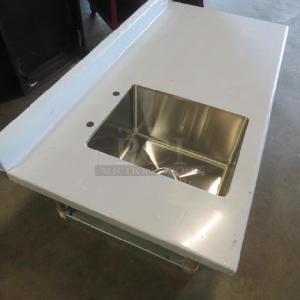 New Advance Tabco stainless steel table with backsplash, sink, and under shelf. No legs, 60x30 inches, sink 16x20 inches, plastic-wrapped.