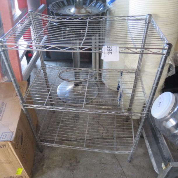 Metro three-shelf wire rack, 23.5x13x31 inches. Sturdy metal construction, used condition. Auction tag visible.