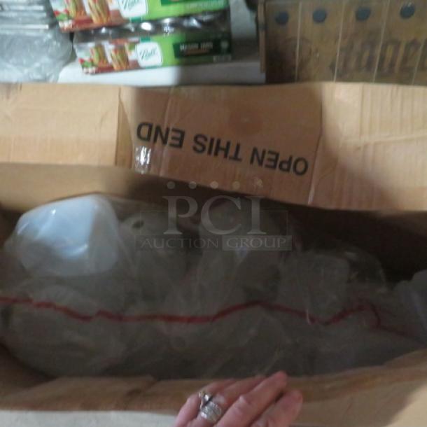 Cardboard box containing multiple new gallon jugs in plastic wrapping, with "Open This End" label visible.