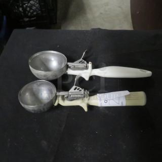 Two metal dishers with white handles on a black surface, labeled "2XBID." In good condition.