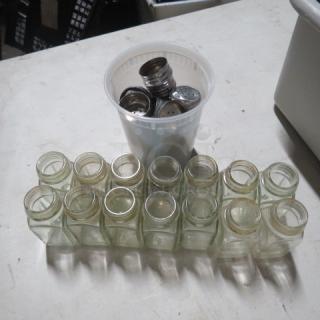 One lot of clear glass salt/pepper shakers, 14 pieces. Shakers are empty with metallic lids, some stacked in a white plastic cup.