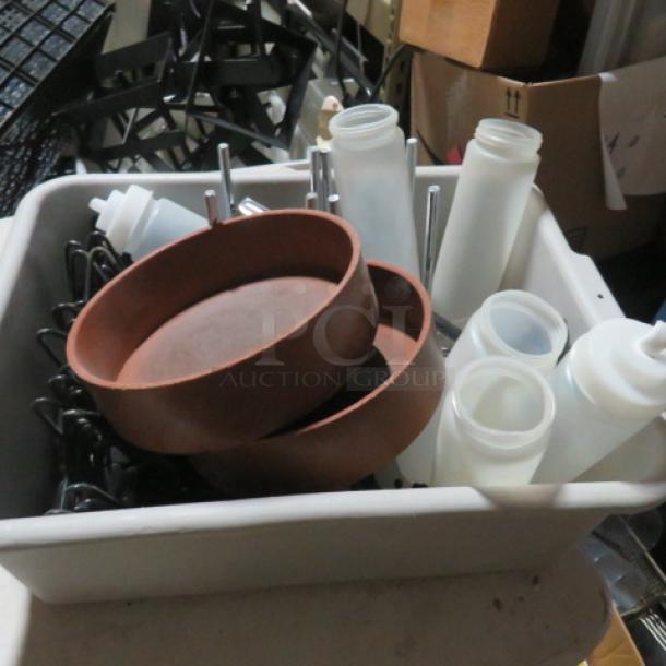 A lot of miscellaneous kitchen items including round brown bowls, plastic condiment squeeze bottles, and metal utensils in a bin.