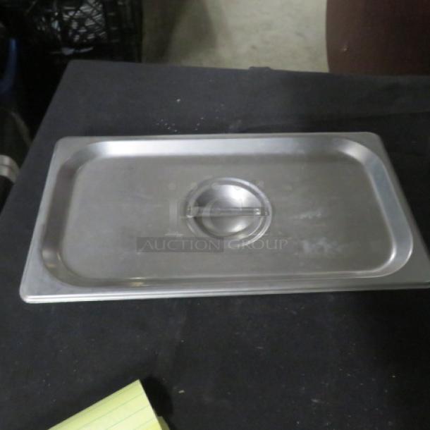 Stainless steel 1/3 size hotel lid, model 7XBID, with handle. Lightly used, shows minor surface wear.