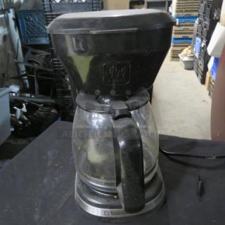 Toastmaster coffee brewer with glass carafe, black exterior, moderate wear. Visible Toastmaster logo on the base. Plugged in.