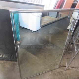 Stainless steel framed mirror, 24x36 inches, in good condition, with a sleek modern design.