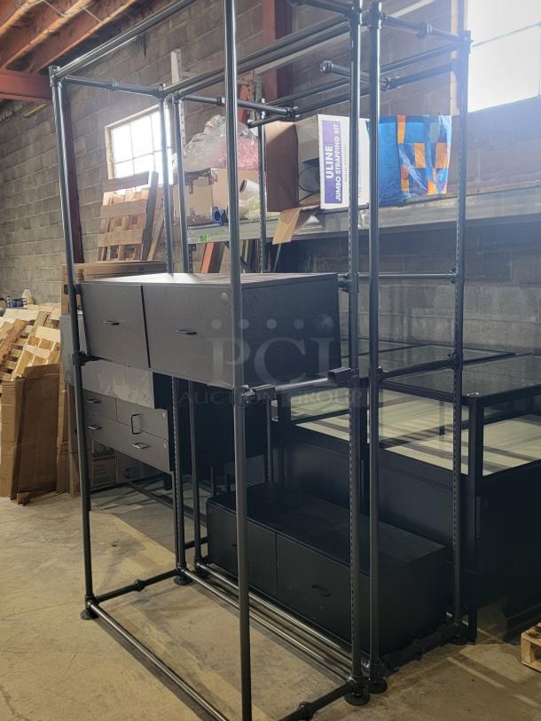 Industrial Pipeline Wall Display by Display Solutions in anthracite grey. Features sturdy metal frame, shelves, and drawers.