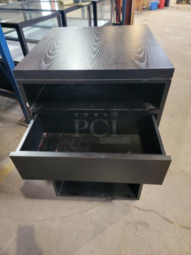 Matte black register stand with top recessed shelf, smooth-glide drawer, adjustable shelving. Durable, high-traffic design.