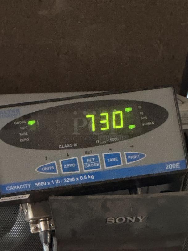 Digital scale displaying 730 pounds, indicating the weight of a stainless steel scrap metal pallet.