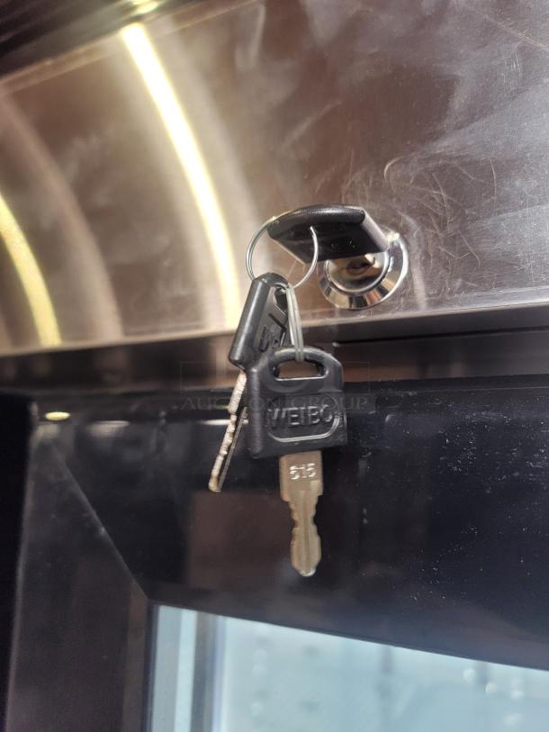 A 2021 North American Restaurant Equipment A2GDF-GR 2-Door Glass Freezer with keys in lock, featuring a bottom-mount compressor.