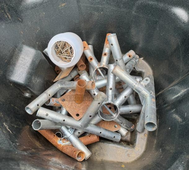 Metal components with rust for assembly of premium 20'x40' frame tent, includes aluminum joints and a container of bolts.