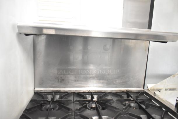 CRC Commercial 6-burner gas range with oven, over shelf, and back splash. Used condition, features sturdy metal build.