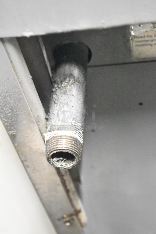 Close-up of a metal gas connection on a CRC commercial gas range. Shows signs of wear and buildup.