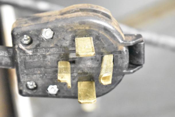 Close-up of a power plug for the Kelvinator T5CHSGHP-4 commercial refrigerator, showing four brass prongs.
