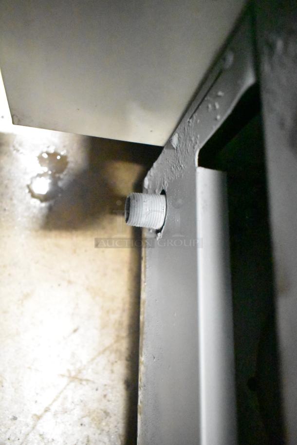 Qualite commercial gas griddle, close-up view, showing gas connection port, sturdy metal construction, appears in used condition.