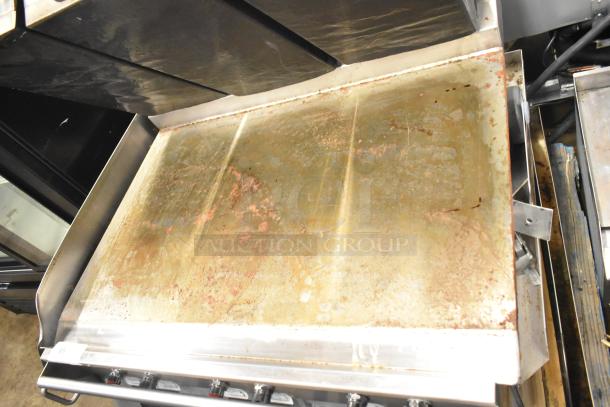 Commercial electric flat top griddle, 3-section panini-style clam shell, visible wear, stainless steel, adjustable controls.