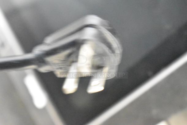 Blurry close-up of a power plug, possibly related to a Menumaster MFS18TS commercial microwave oven.