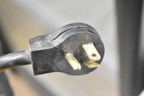 Close-up of a three-prong plug for an Imbera VR10 Commercial Reach In Cooler. Black casing with visible wear.