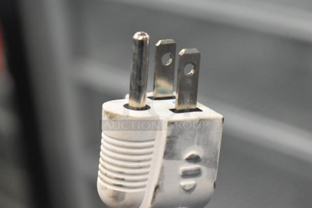 Close-up of a three-prong power plug from an Accucold ARG3PV456 mini cooler, showing slight wear.