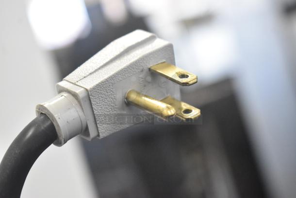 Power plug for True GDM-41SL-48-HC-LD cooler, 115 volts, 1 phase. Close-up of prongs and textured casing.