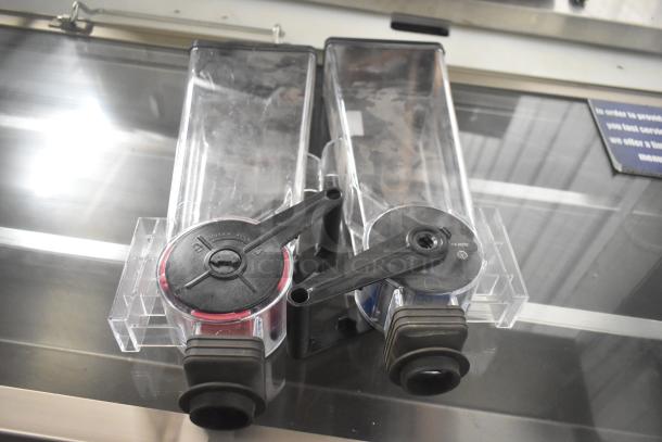 Server countertop dry dispenser, dual clear containers with black dispensing levers, in good condition, on stainless surface.