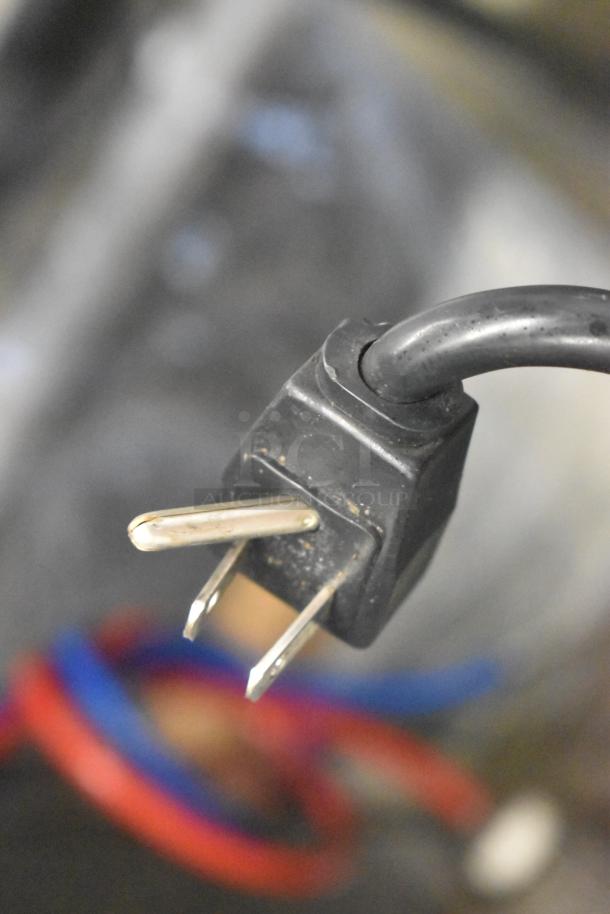 Close-up of Manitowoc QM45A ice machine power plug, 115 volts, 1 phase, showing standard electrical prongs.