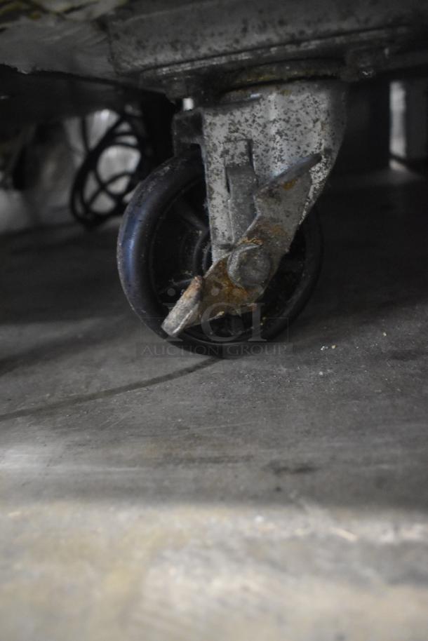 Close-up of a caster wheel on the Avantco 178AWT48FHC stainless steel commercial 2-door work top freezer.