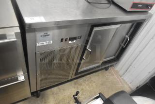 Commercial 2 Door Back Bar Cooler with stainless steel finish, on casters. Features control panel and ventilation grille.