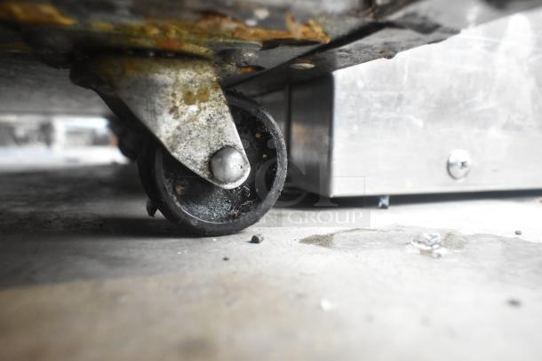 Delfield 406CA-DD1 undercounter cooler's commercial caster, showing wear and surface rust. 115V, 1 phase connection.