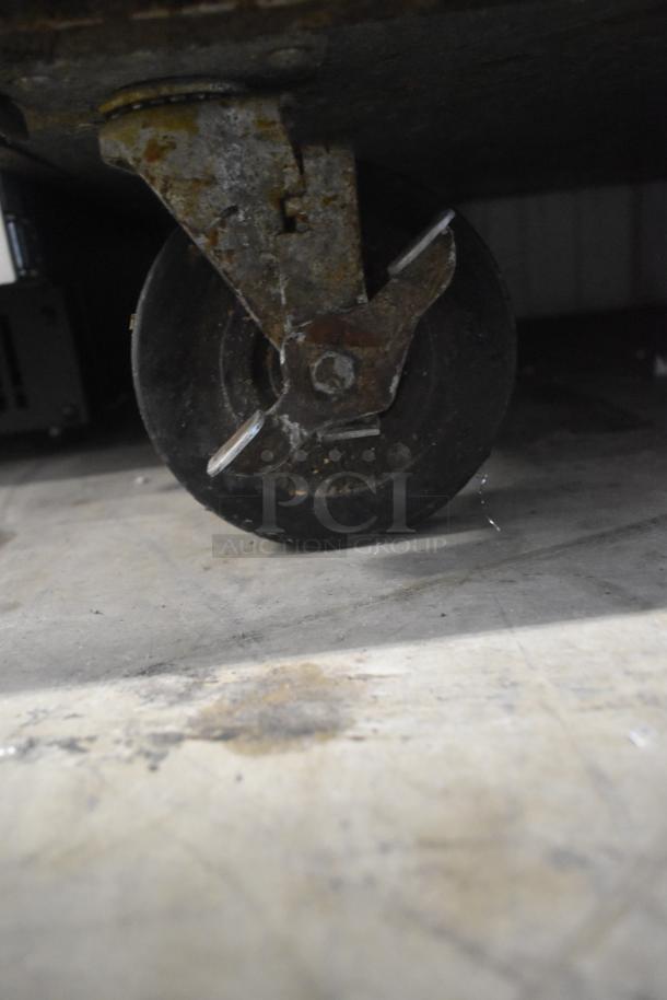 Close-up of a caster on a 2019 True TPP-67 Stainless Steel Pizza Prep Table, showing rust and wear.