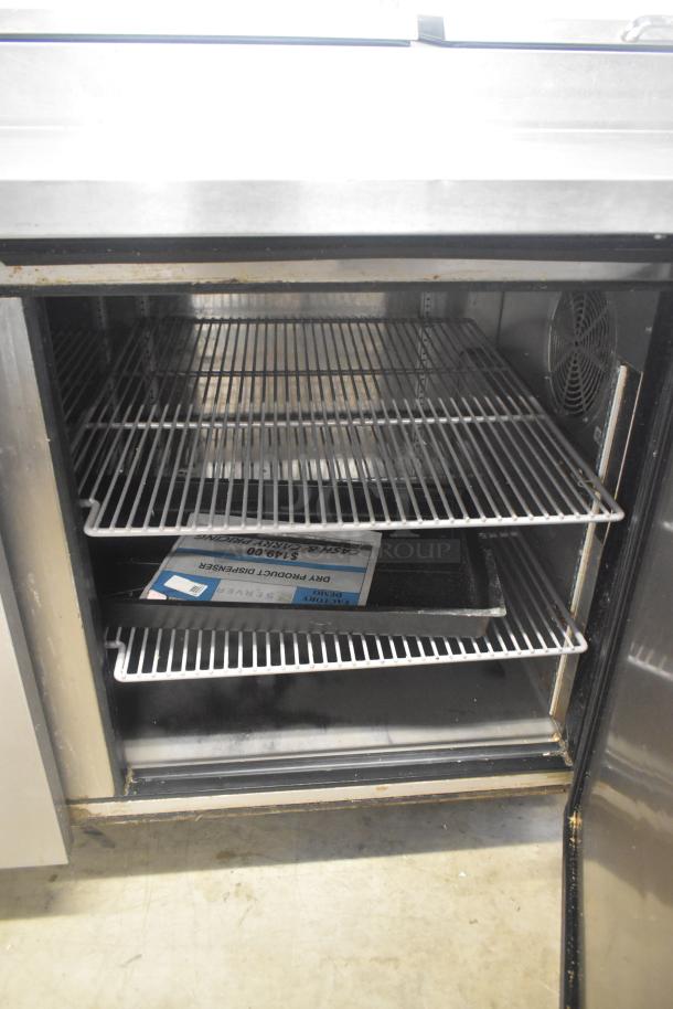 2019 True TPP-67 stainless steel pizza prep table, featuring commercial casters, open shelving, and 115V power.