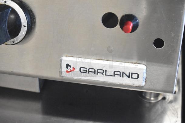 Garland GTGG60 commercial griddle, stainless steel with manual controls, natural gas-powered. Logo label visible.