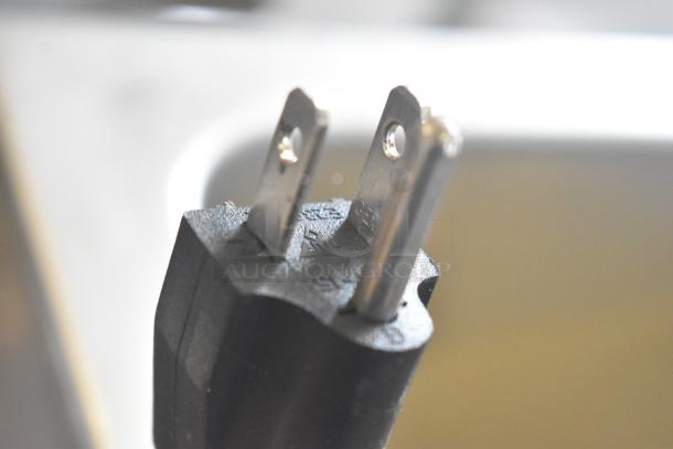 Close-up of a power plug for an Adcraft FW-1500W/C countertop food warmer, 120 volts, 1 phase, showing metal prongs.