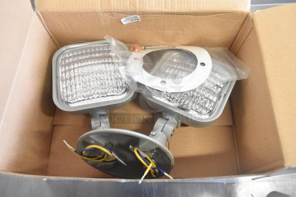 Box of four new scratch and dent lighting fixtures, including VLED-EL90 exit sign, with mounting hardware.