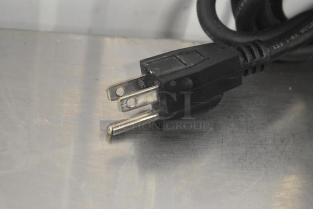 Winco FW-S500 food warmer plug, black with three prongs, 120 volts, 1 phase, visible wear on the metallic surface.