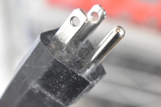 Close-up of a three-pronged electrical plug, likely for the Imperia NSP Countertop Pasta Machine. Plug shows minor surface wear.